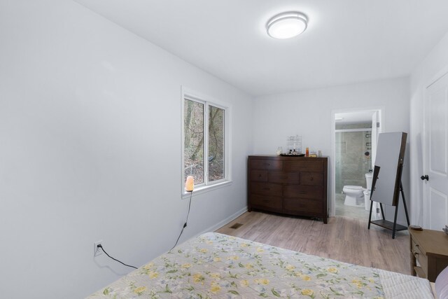 bedroom featuring light wood-type flooring and connected bathroom