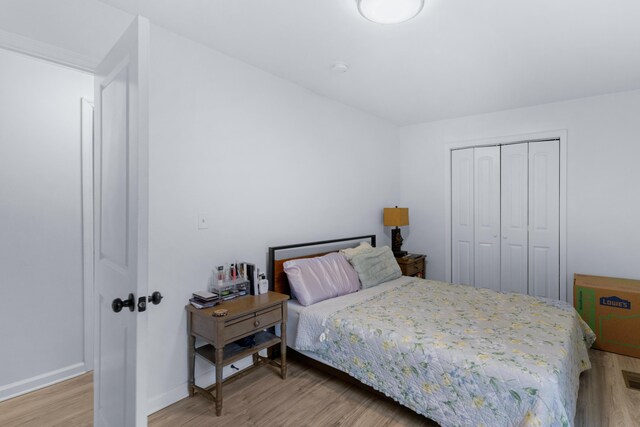 bedroom with light hardwood / wood-style floors and a closet