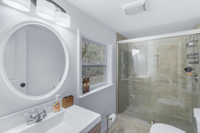 bathroom featuring a shower with door, vanity, toilet, and tile patterned flooring