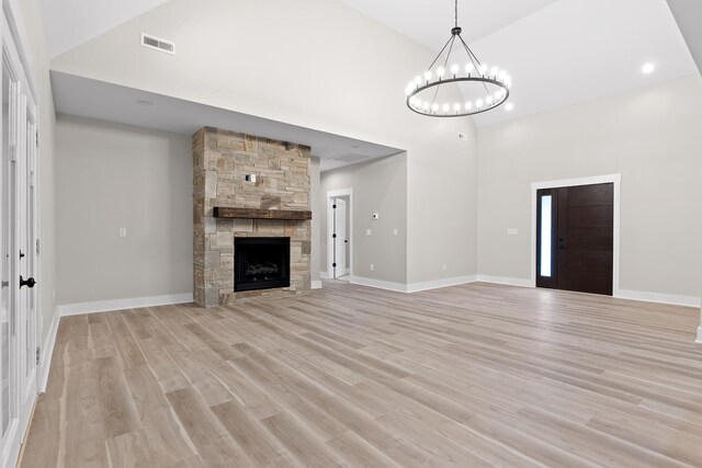 unfurnished living room with a fireplace, light hardwood / wood-style flooring, and a notable chandelier