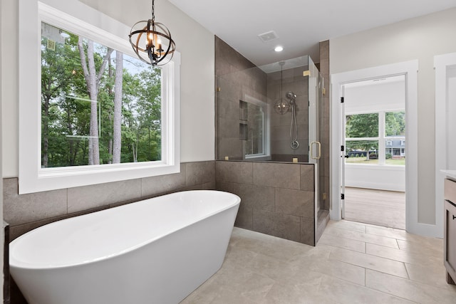 bathroom featuring tile patterned flooring, vanity, shower with separate bathtub, and a chandelier