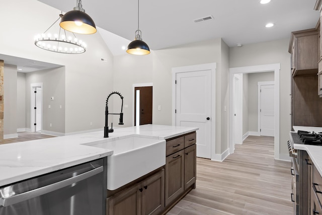 kitchen featuring light stone counters, stainless steel appliances, sink, pendant lighting, and an inviting chandelier