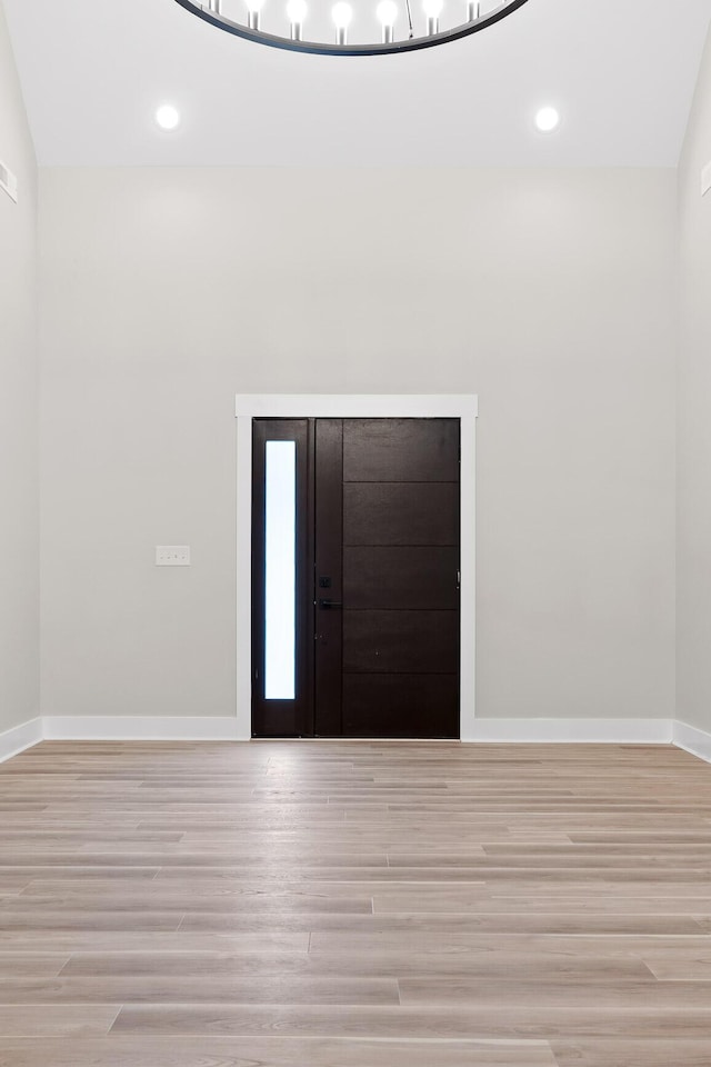 foyer entrance with light hardwood / wood-style floors and lofted ceiling