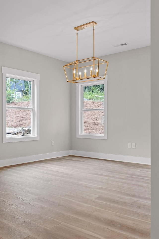 unfurnished room featuring light wood-type flooring and a chandelier