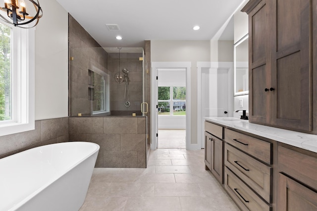 bathroom with vanity, an inviting chandelier, tile patterned flooring, tile walls, and independent shower and bath