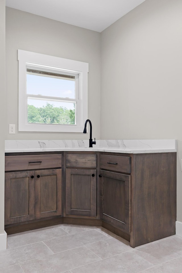 interior space with dark brown cabinetry, light stone counters, and sink