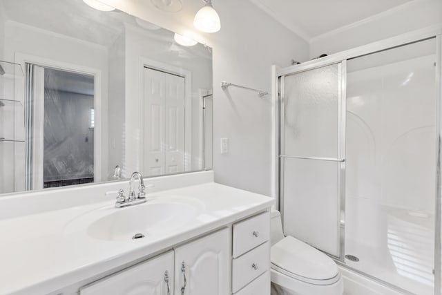 bathroom with a shower with shower door, vanity, toilet, and ornamental molding