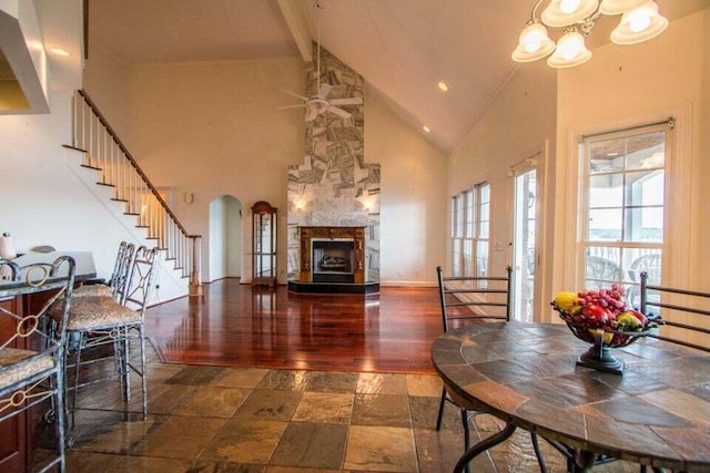 dining room featuring a fireplace, high vaulted ceiling, a chandelier, and beamed ceiling