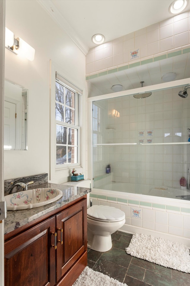 full bathroom with ornamental molding, vanity, combined bath / shower with glass door, and toilet