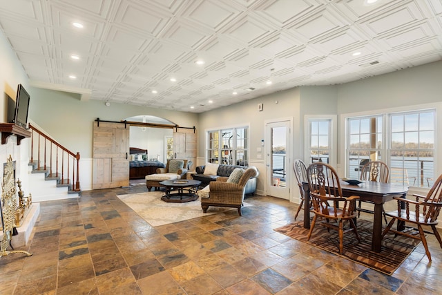 living room with a high ceiling, a barn door, a water view, and plenty of natural light