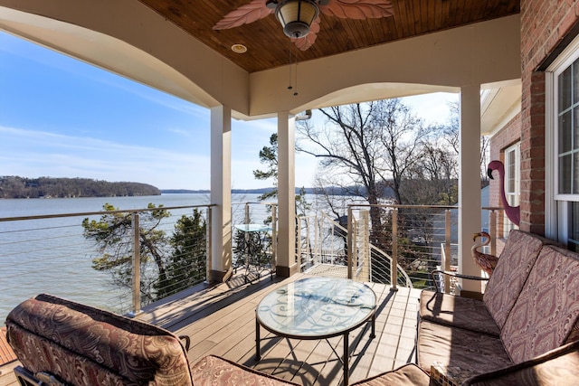 wooden deck with a water view and ceiling fan