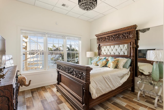 bedroom featuring a drop ceiling and multiple windows