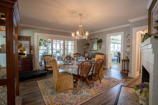 dining area featuring ornamental molding, a notable chandelier, a fireplace, and dark wood finished floors