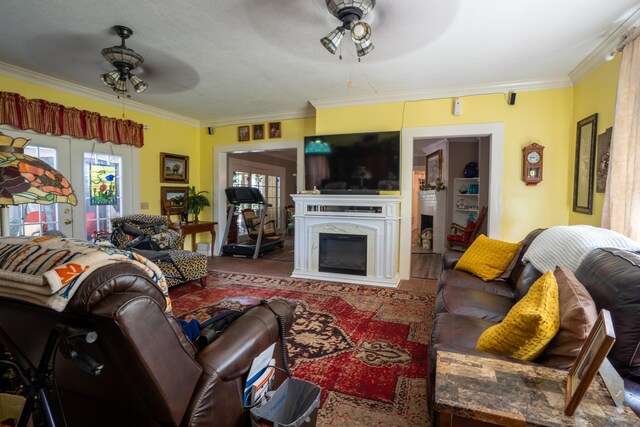 living room with ornamental molding, a fireplace, ceiling fan, and french doors