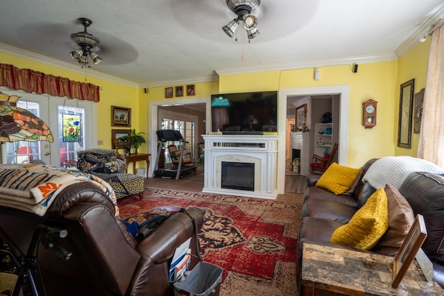 living area with a high end fireplace, crown molding, and a ceiling fan