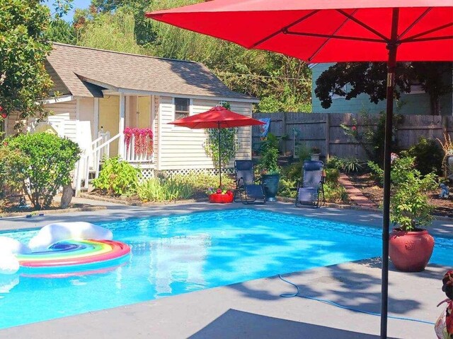 view of pool featuring a patio area, an outbuilding, and a hot tub