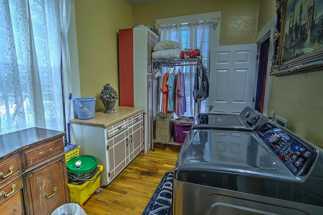 laundry room with washer and clothes dryer, cabinets, and light wood-type flooring