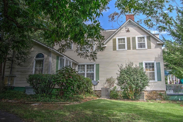 view of side of property featuring central AC unit and a lawn