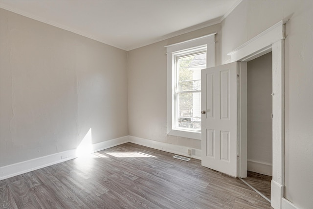 spare room with wood-type flooring and crown molding