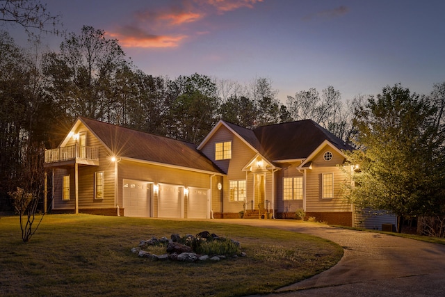 view of front of house with a garage, a balcony, and a lawn