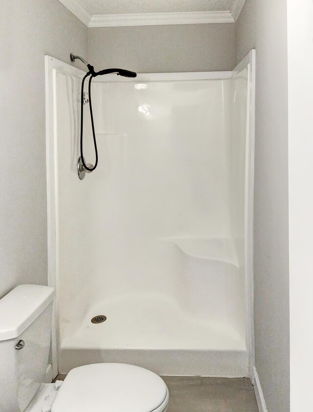 bathroom featuring ornamental molding, toilet, and a shower