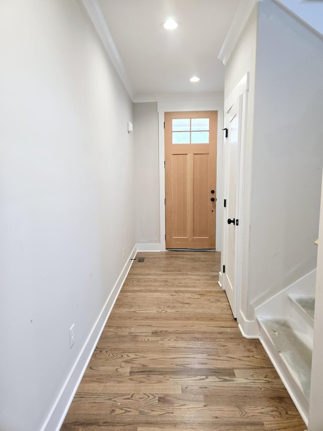 doorway with light hardwood / wood-style floors and crown molding