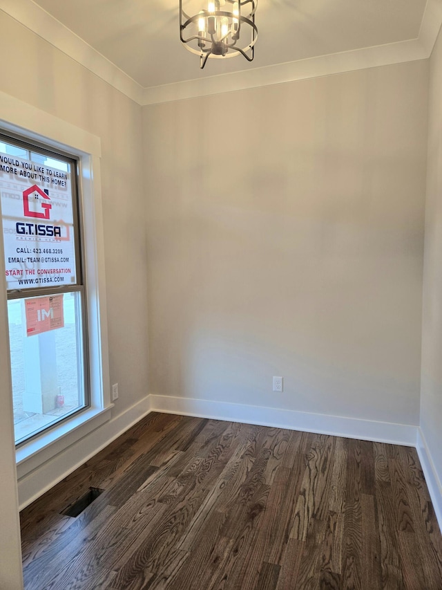 unfurnished room featuring dark hardwood / wood-style flooring, ornamental molding, and a notable chandelier