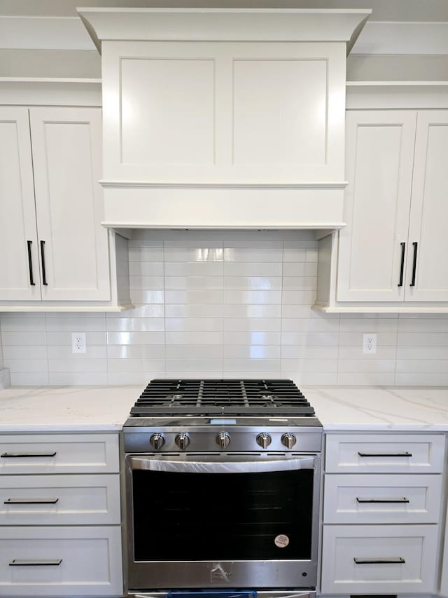 kitchen featuring decorative backsplash, gas stove, and white cabinetry