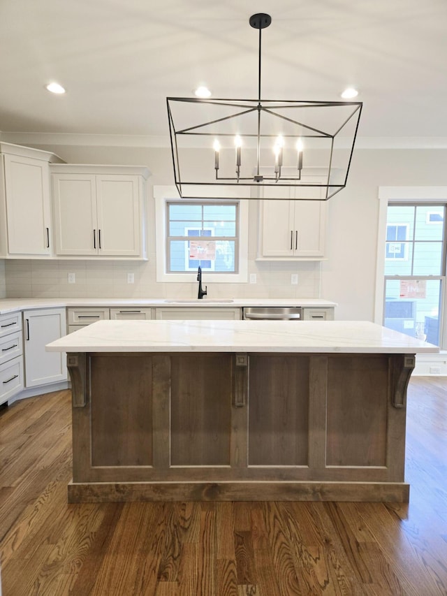 kitchen featuring dark wood-type flooring, white cabinets, crown molding, sink, and a kitchen island