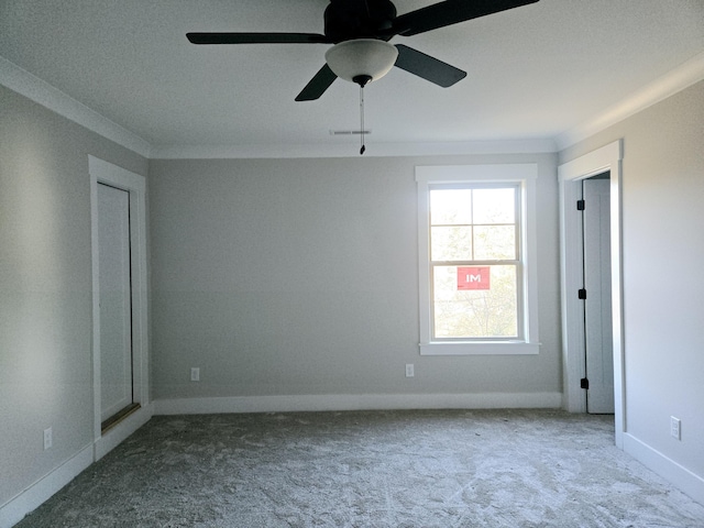 carpeted spare room with ceiling fan and ornamental molding