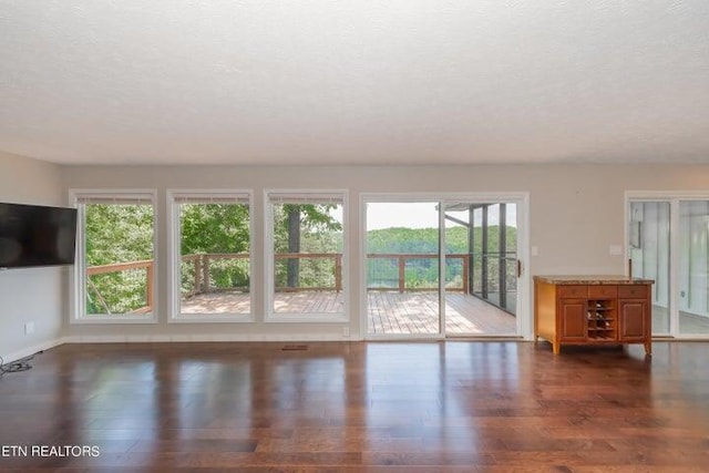 unfurnished living room with a textured ceiling and dark hardwood / wood-style flooring