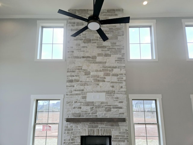 interior details featuring a fireplace, ceiling fan, and crown molding