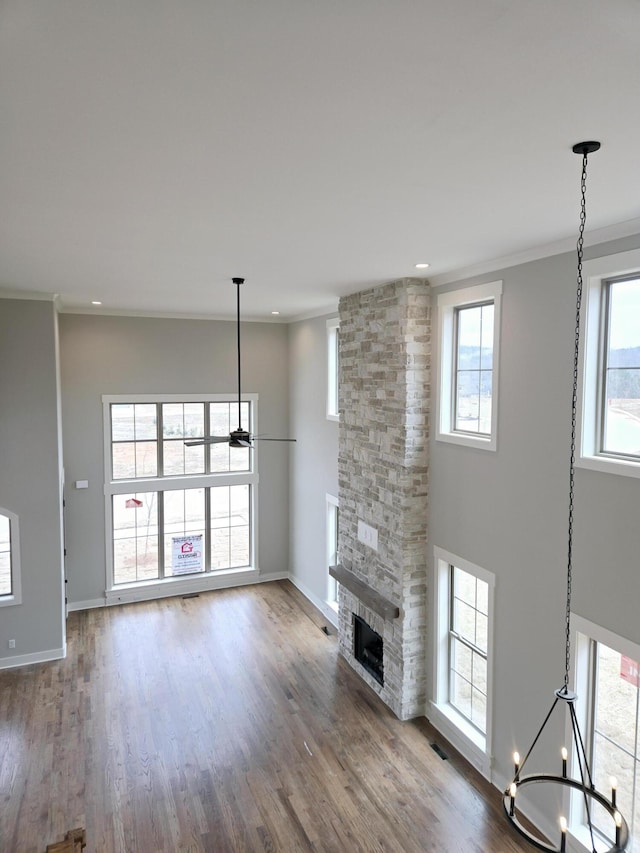 unfurnished living room with hardwood / wood-style floors, plenty of natural light, a fireplace, and a notable chandelier