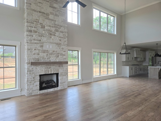 3297 Grassland Cir Unit 7, Apison, TN 37302 - unfurnished living room featuring a towering ceiling, wood finished floors, a stone fireplace, and visible vents