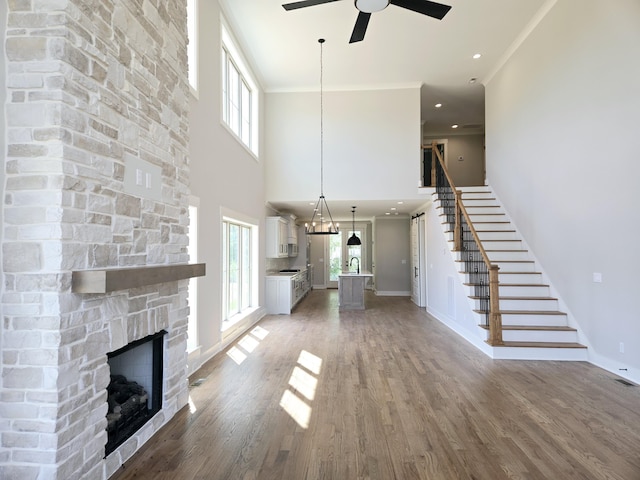 3297 Grassland Cir Unit 7, Apison, TN 37302 - unfurnished living room featuring stairs, a stone fireplace, baseboards, light wood-style floors, and ceiling fan with notable chandelier
