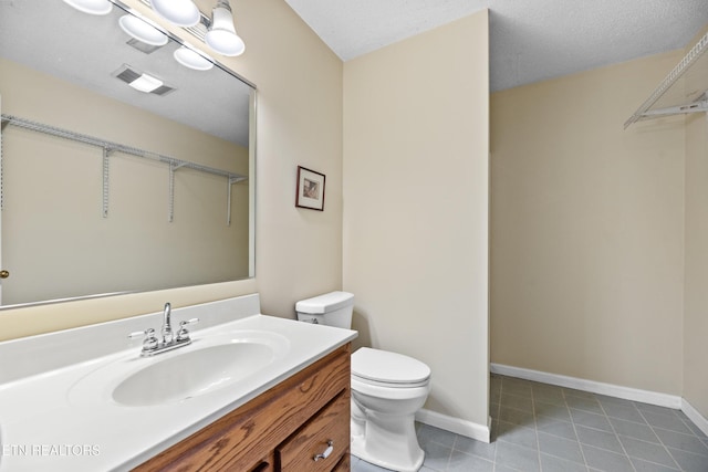 bathroom with a textured ceiling, vanity, and toilet