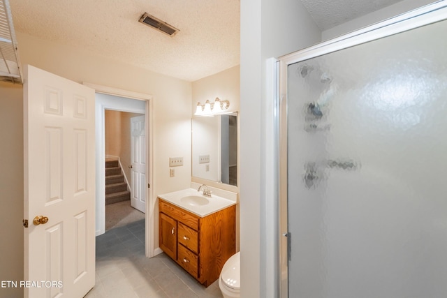 bathroom featuring tile patterned floors, vanity, an enclosed shower, and a textured ceiling