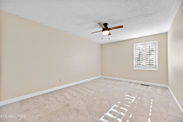 spare room featuring ceiling fan, light colored carpet, and a textured ceiling