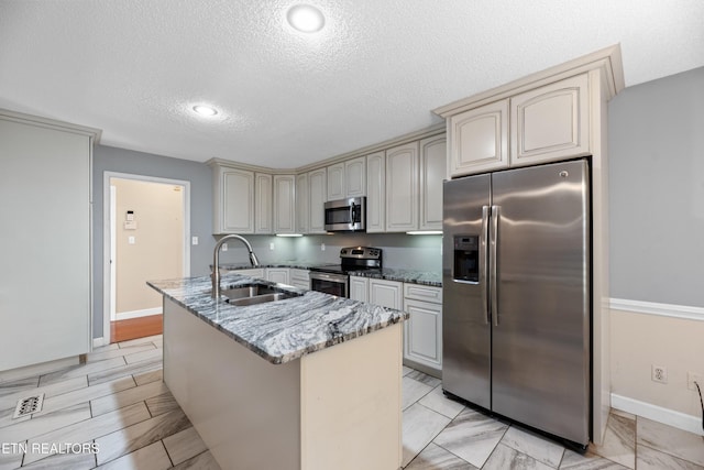 kitchen featuring stone counters, cream cabinetry, stainless steel appliances, and sink