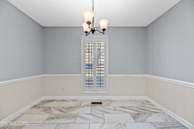 spare room with french doors, a textured ceiling, and a notable chandelier