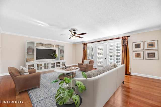 living room featuring a textured ceiling, light wood-type flooring, ceiling fan, and ornamental molding