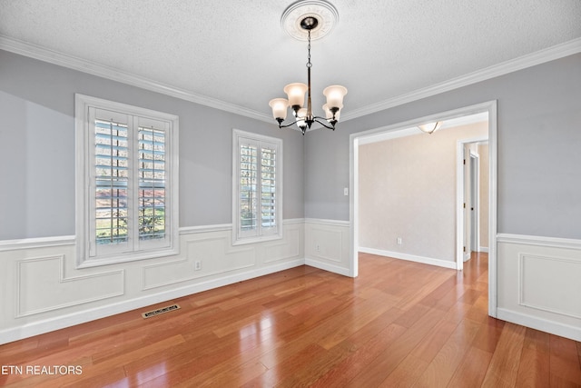 interior space featuring light hardwood / wood-style floors, ornamental molding, a textured ceiling, and a chandelier