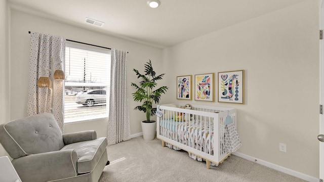 carpeted bedroom featuring multiple windows and a crib