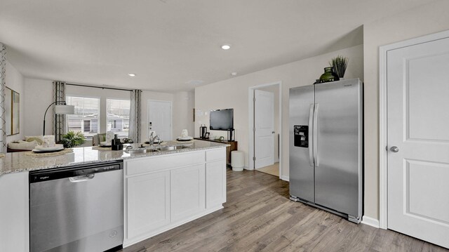 kitchen featuring white cabinetry, sink, light stone counters, light hardwood / wood-style floors, and stainless steel appliances