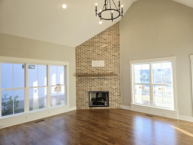 unfurnished living room with high vaulted ceiling, a fireplace, a chandelier, and hardwood / wood-style flooring