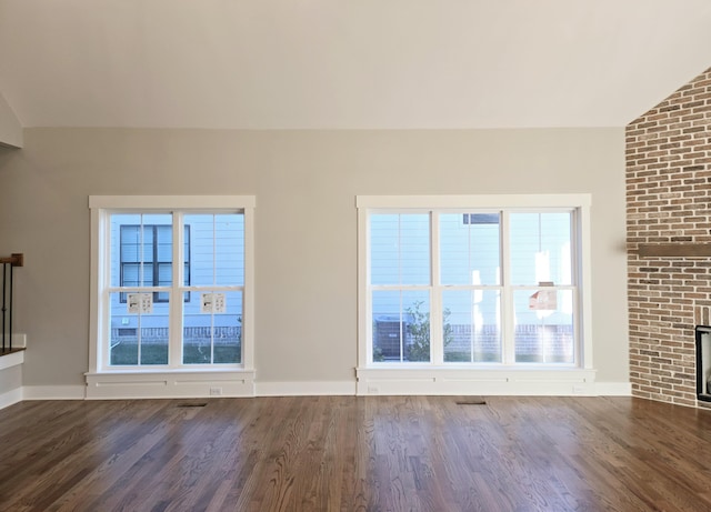 unfurnished living room featuring lofted ceiling, a fireplace, and dark hardwood / wood-style floors