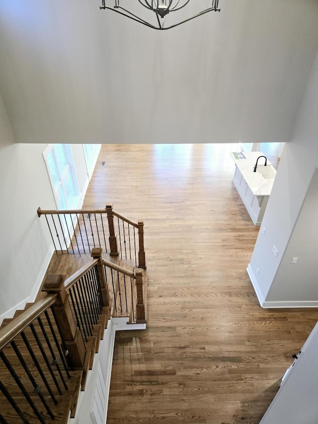 staircase with wood-type flooring and a chandelier