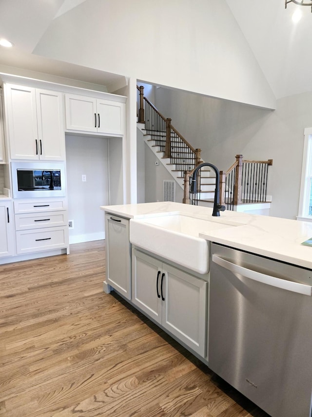 kitchen featuring black microwave, dishwasher, white cabinets, and sink