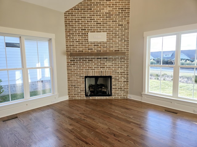 unfurnished living room with dark hardwood / wood-style flooring, lofted ceiling, and a fireplace