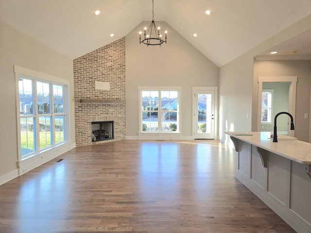 unfurnished living room with a wealth of natural light, a fireplace, sink, and dark hardwood / wood-style flooring